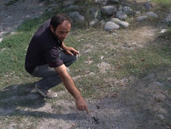 Zviad Geladze, 38, points to a cluster munition strike on the path to his farm field 