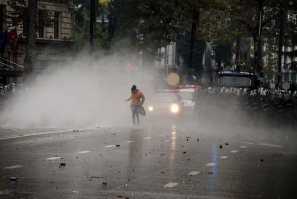 A girl flees after riot police attack protestors with tear gas and rubber bullets in downtown Tbilisi on November 7, 2007.