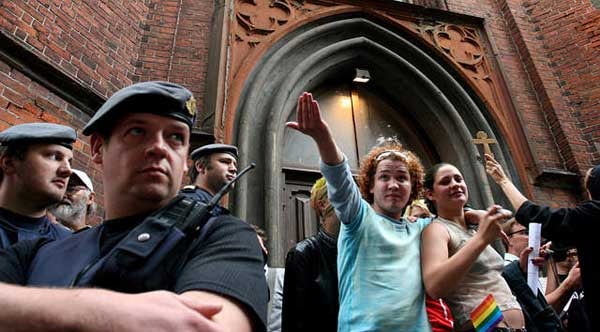 8.Policemen watch participants at an ecumenical service at an Anglican Church during the first Gay Pride in Riga, Latvia, while anti-gay demonstrators threaten them, July 23 © 2005 Reuters Limited.

