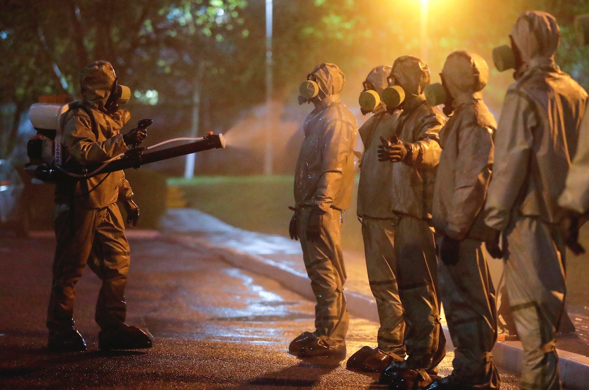 Servicemen of Belarus Ministry of Defence wearing protective gear spray disinfectant on each other after disinfecting a hospital in Minsk