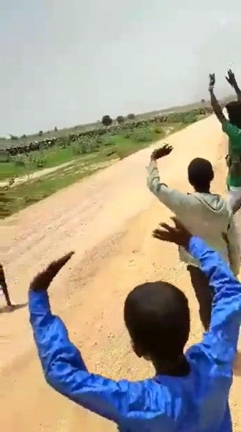 Children with their hands raised on the side of a rural road