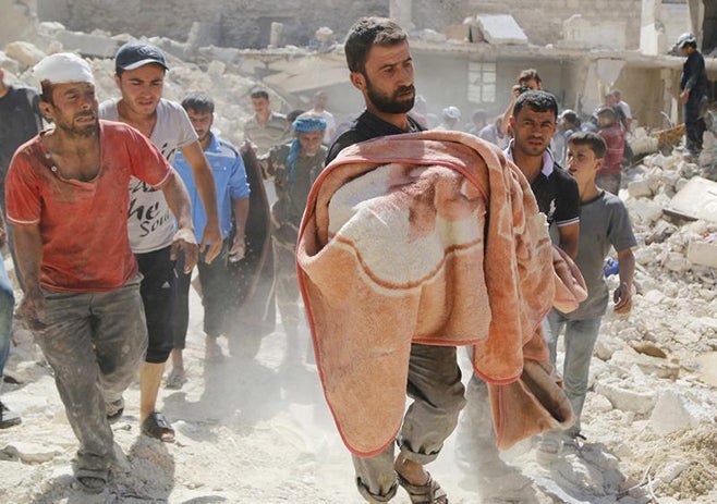 Relatives mourn as a man carries the body of a dead boy in a blanket at a site hit by what activists said was a barrel bomb dropped by forces loyal to Syria's President Bashar al-Assad in the Sheikh Khodr area in Aleppo on September 30, 2014.