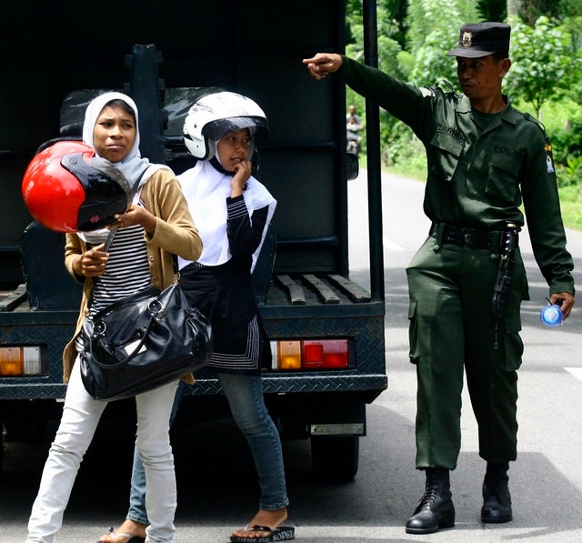 A sharia police officer escorts women caught wearing tight pants during a street raid in Arongan Lambalek district in Indonesia's Aceh province on May 26, 2010.