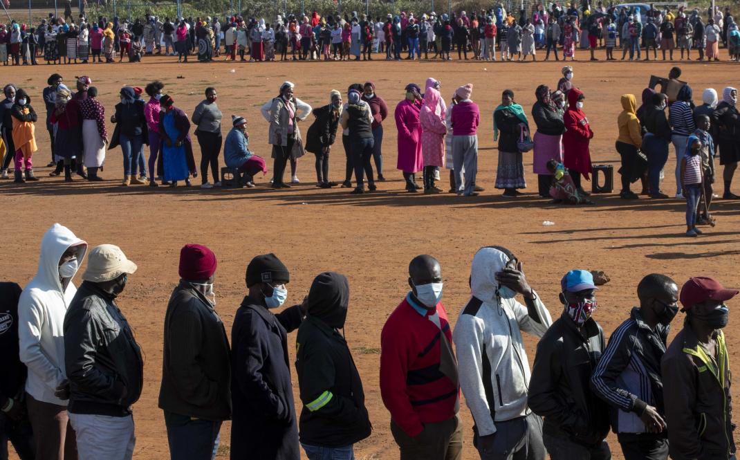 People affected by the coronavirus economic downturn, line up to receive food donations at the Iterileng informal settlement near Laudium, southwest of Pretoria, South Africa, Wednesday, May 20, 2020.