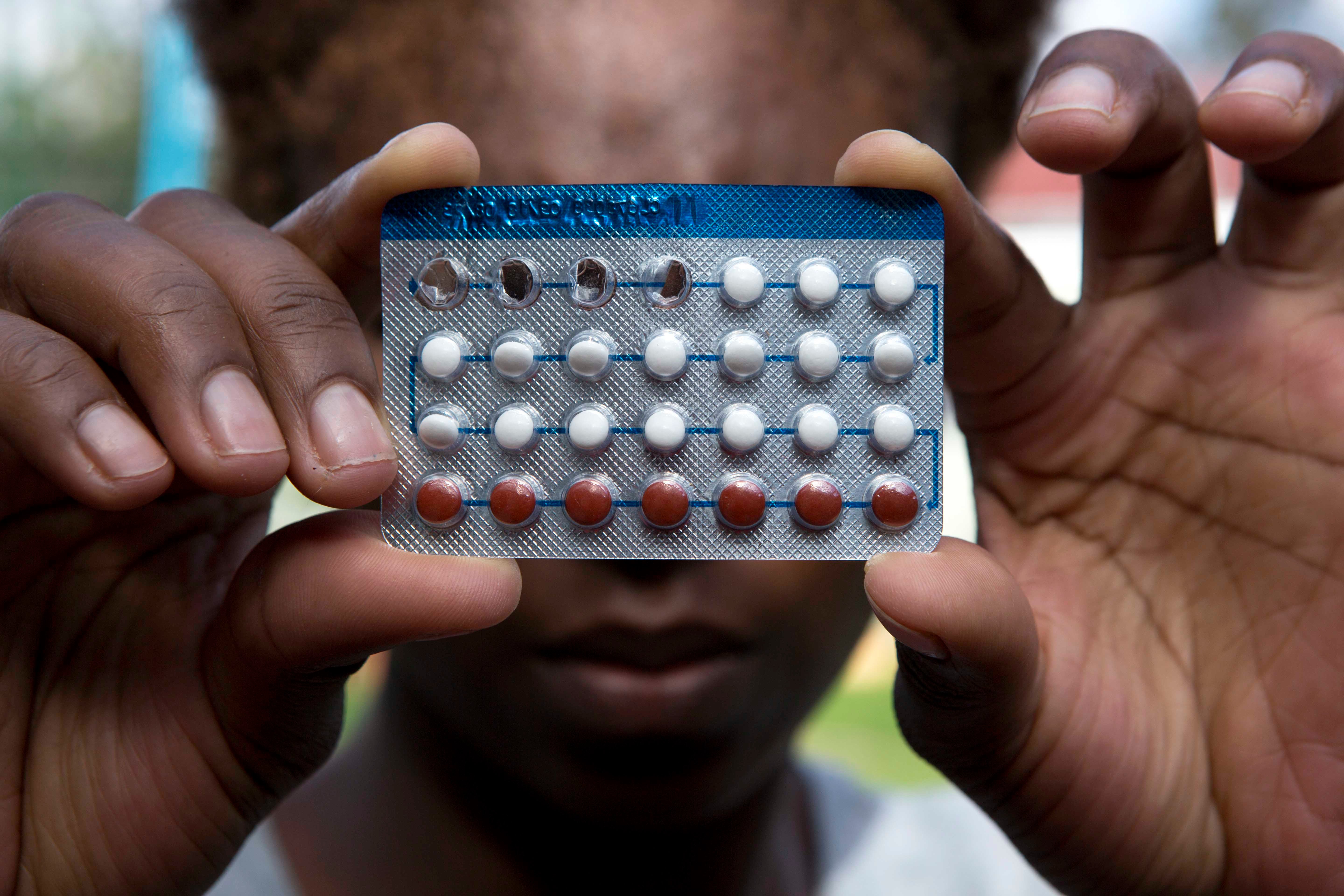 A woman holds a packet of contraceptive pills, in Harare, Thursday, April 9, 2020.