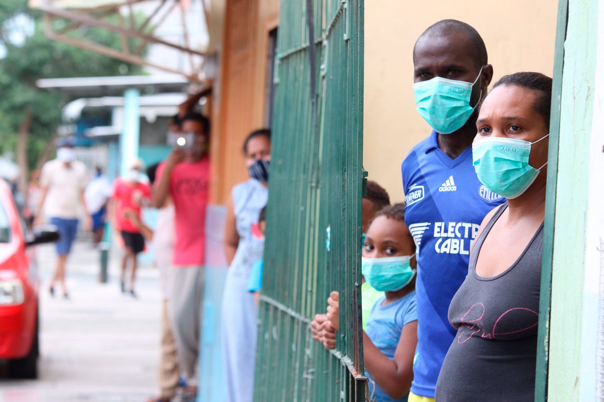 Familias con mascarillas esperan afuera de sus hogares en el barrio de Cristo del Consuelo para recibir alimentos del gobierno local en Guayaquil, Ecuador, el 14 de abril de 2020.