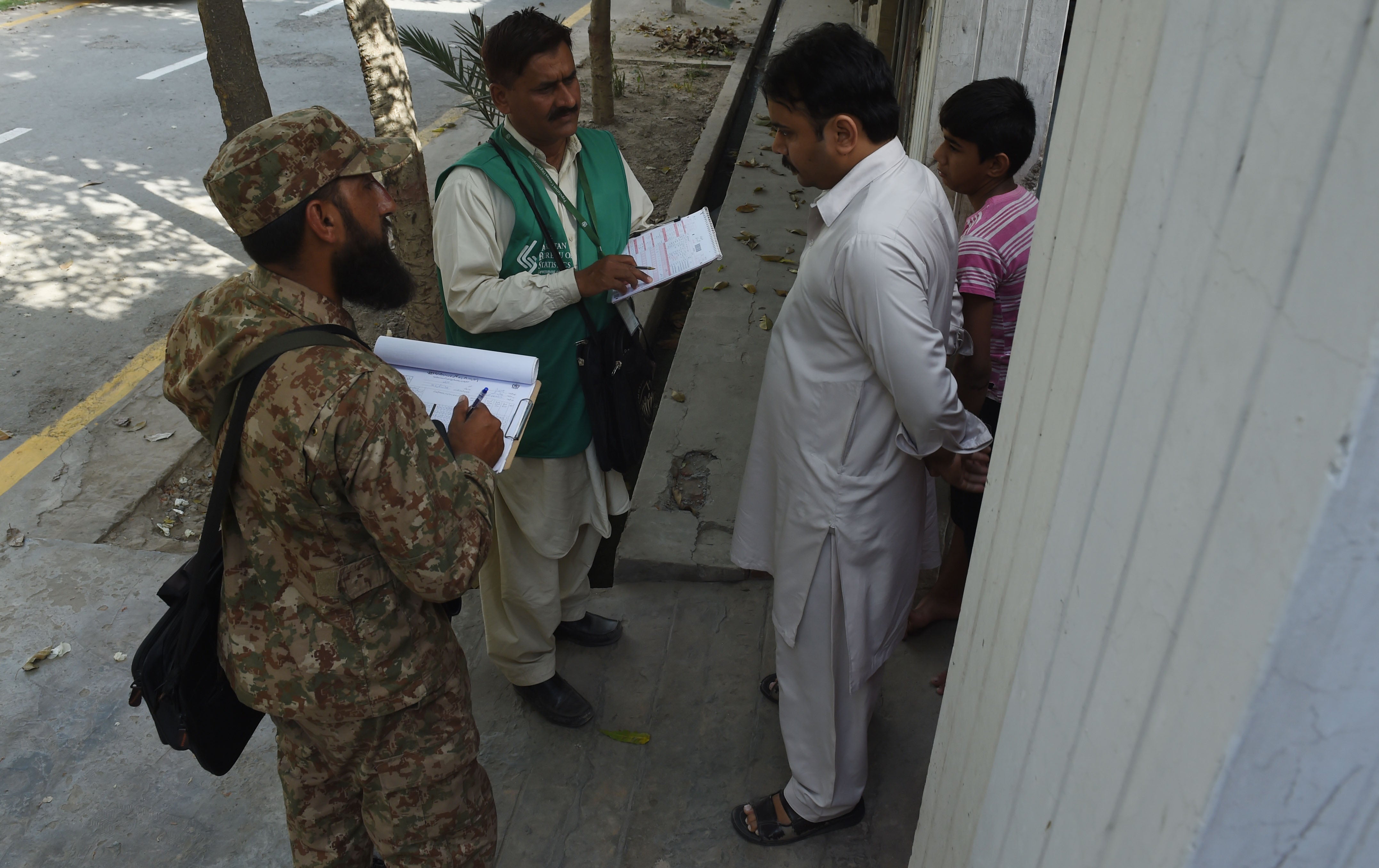 A Pakistan Bureau of Statistics official and a soldier collect census information from an Ahmadi resident in Rabwah, Punjab, Pakistan in March 2017. © 2017 ARIF ALI/AFP via Getty Images