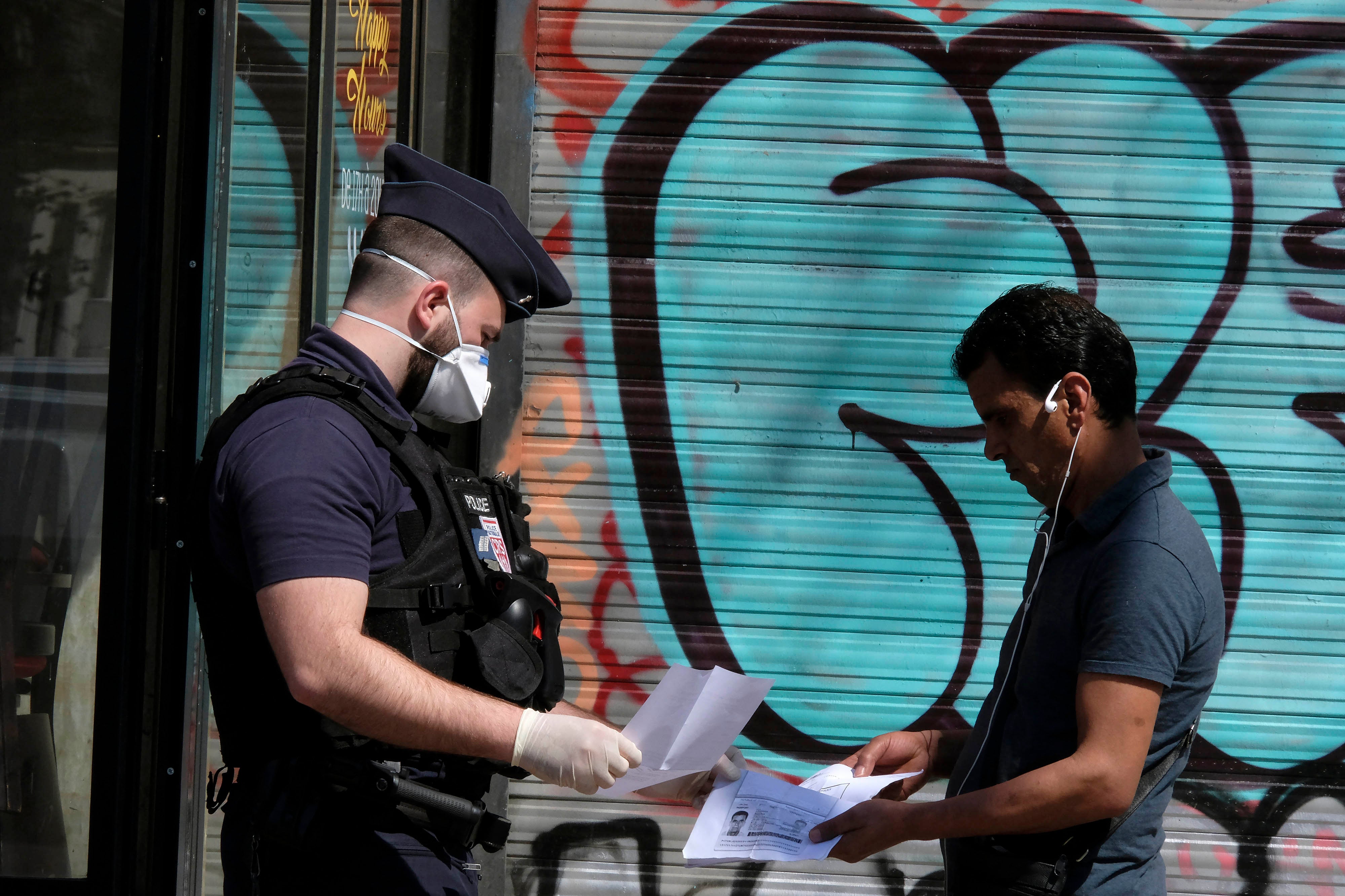 Un policier français portant un masque chirurgical de protection contre le coronavirus, contrôle les papiers d'un homme à Paris, alors qu'une quarantaine stricte est en vigueur en France pour arrêter la propagation de COVID-19. Paris, France, le 16 avril 2020. 