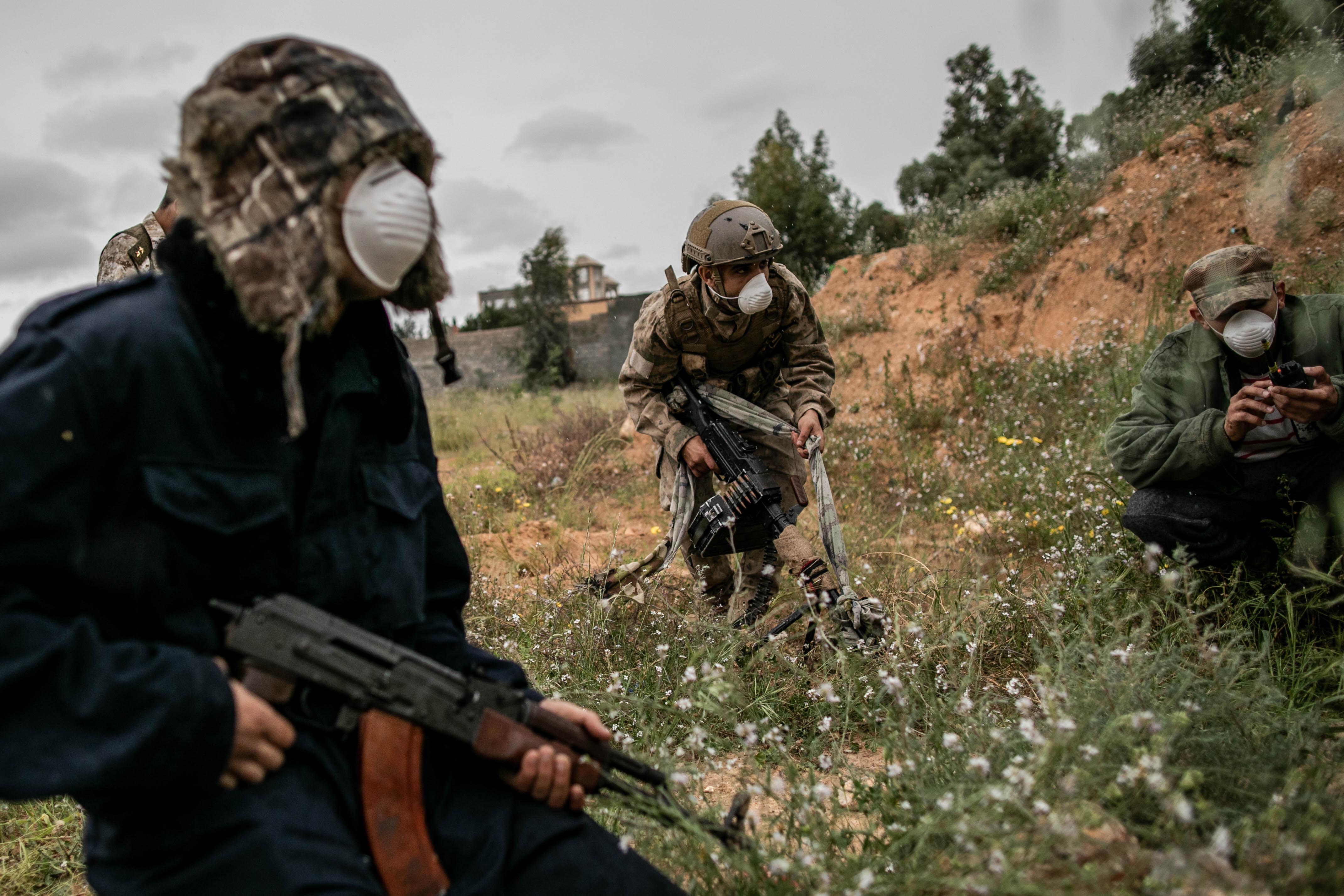 Three men in full combat gear wearing protective face masks against Covid-19, in Tripoli, Libya on March 25, 2020.