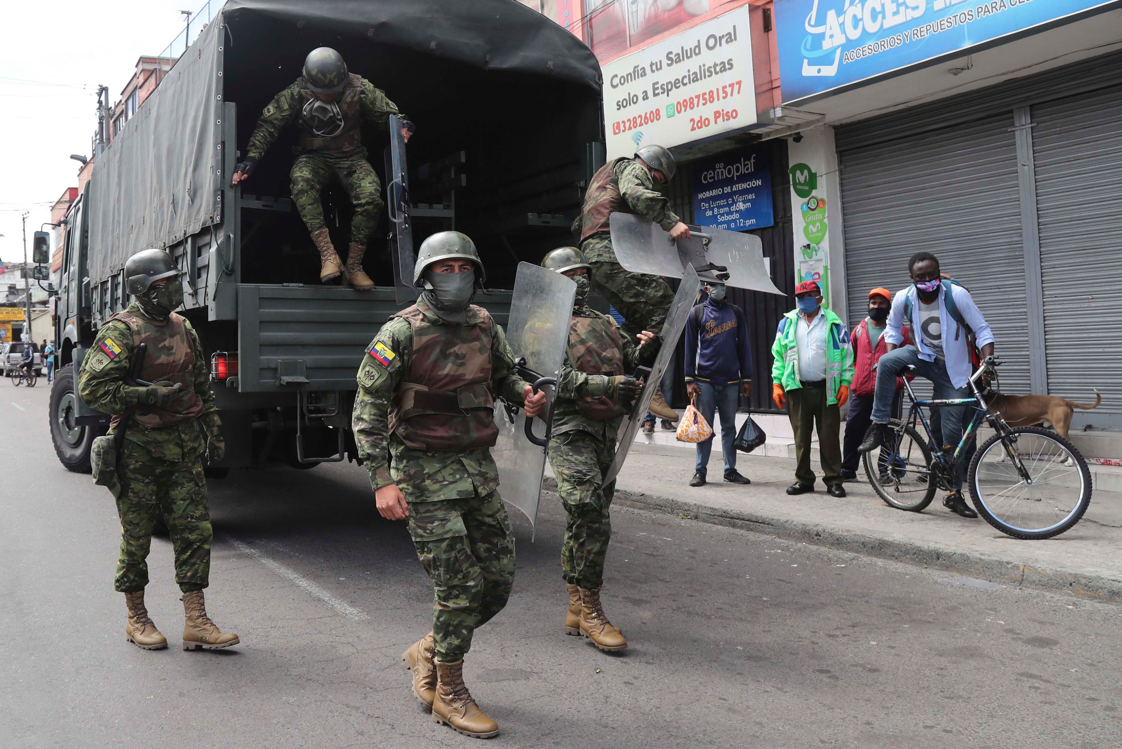 Soldiers in riot gear arrive to reinforce authorities after street merchants protested the seizure of their merchandise by the municipal police of Quito, Ecuador, Thursday, May 21, 2020.