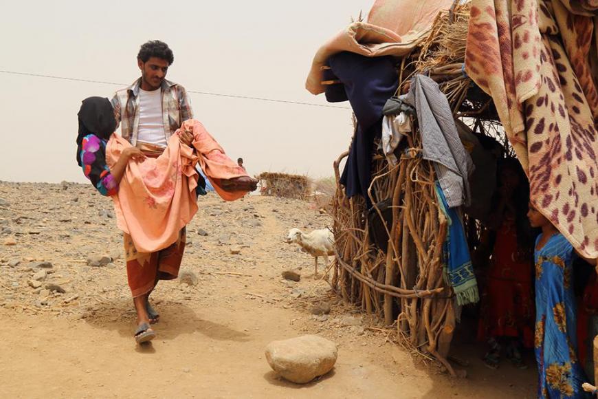 A woman is carried by her brother outside a home in Malus, Yemen. 