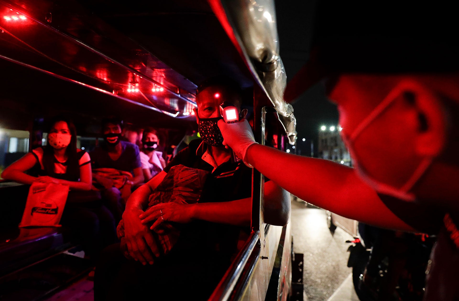 A police officer checks the temperatures of passengers inside a jeepney at a checkpoint in Manila, Philippines, March 16, 2020. 