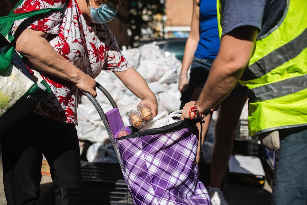 A woman receives donated food from the Aluche Neighborhood Association headquarters where volunteers have delivered food and donated products for those in need amid coronavirus outbreak, in Madrid, Spain.