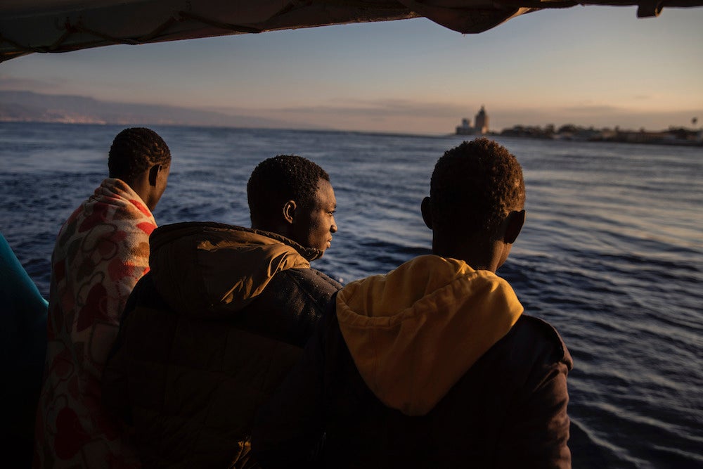 Men who were rescued off the Libyan coast in January, 2020 watch the city of Messina, Sicily from the deck of the Open Arms rescue vessel.