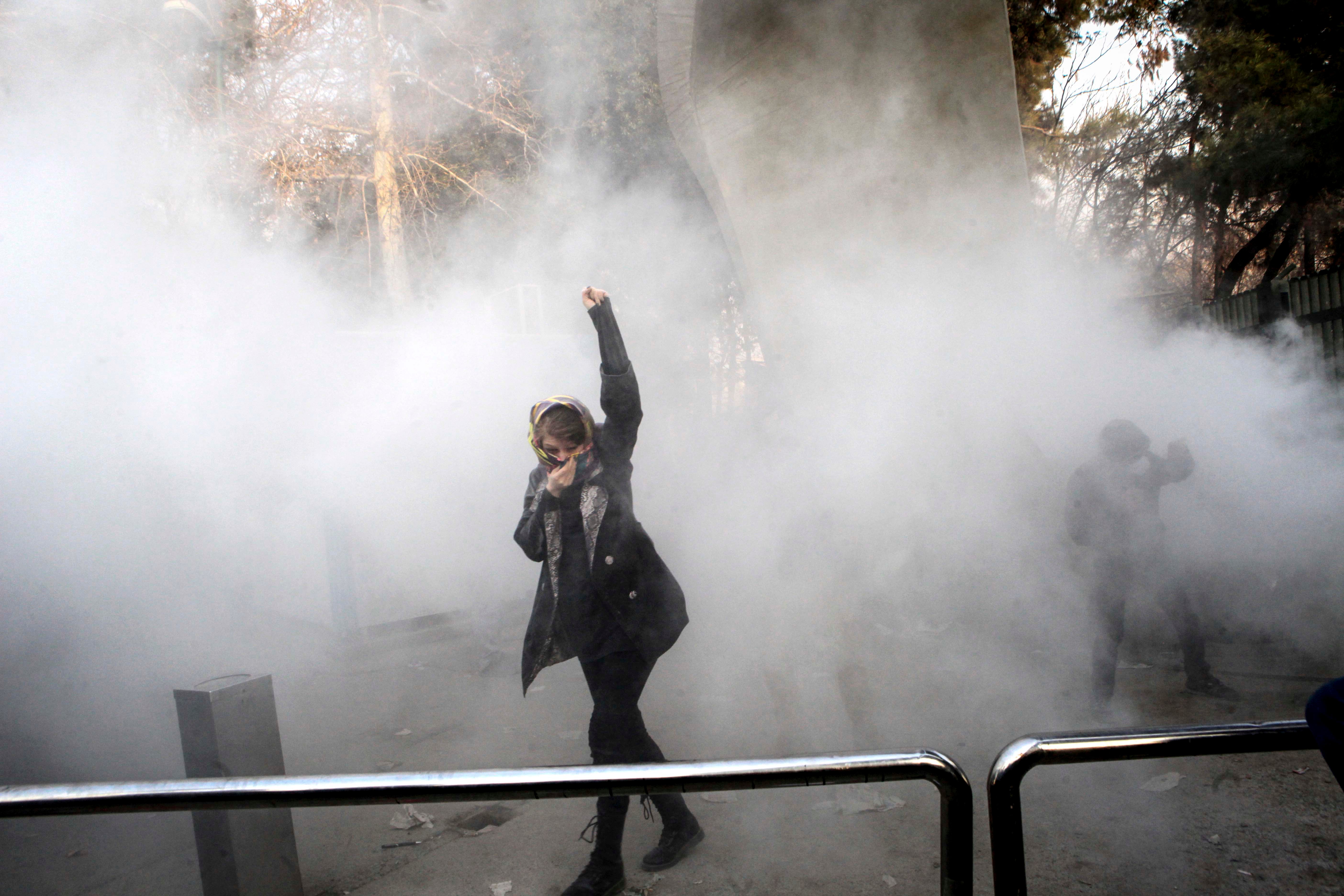 On December 30, 2017, a university student attends a protest inside Tehran University while a smoke grenade is thrown by anti-riot Iranian police, in Tehran, Iran.