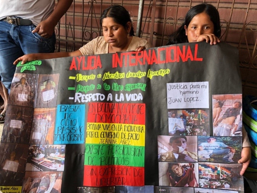 Two women hold up a banner in Spanish