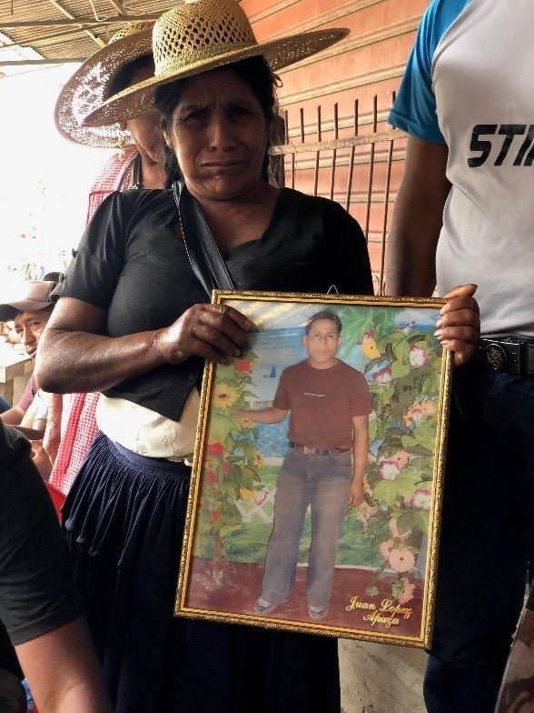 A woman holds up a framed photo of a young man