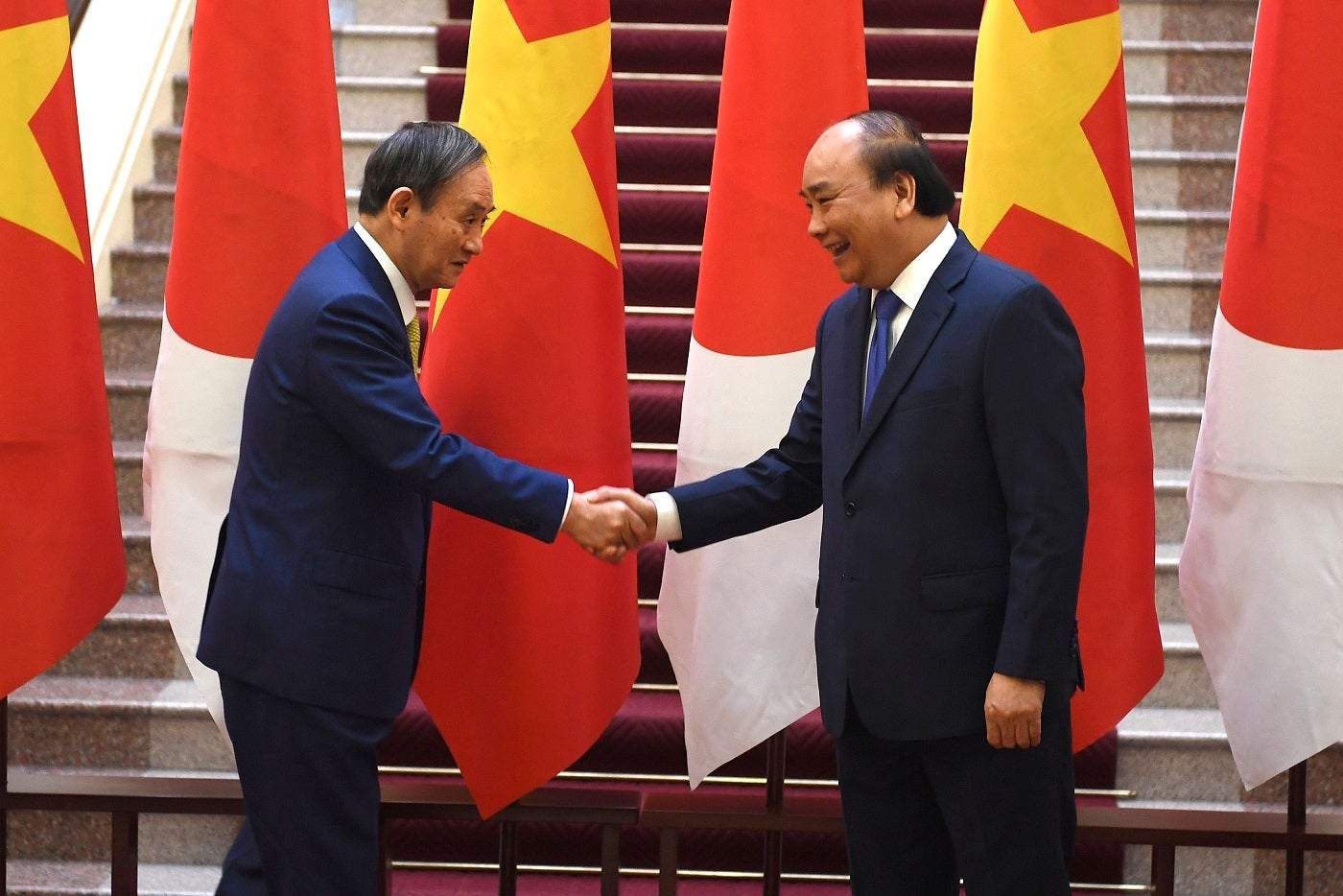 Japan's Prime Minister Yoshihide Suga, left, shakes hands with Vietnam's Prime Minister Nguyen Xuan Phuc after the exchange of documents at the Government Office in Hanoi on Monday, October 19, 2020. 