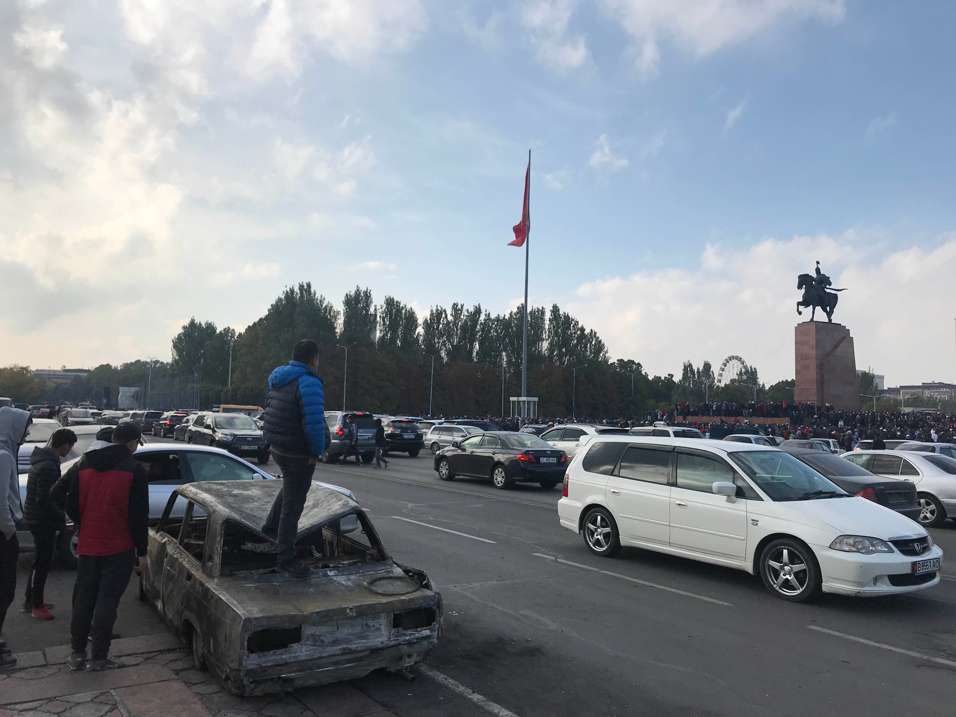 A man stands on a burnt out car following a night of unrest in connection with protests against the October 4 parliamentary vote in Bishkek, Kyrgyzstan.