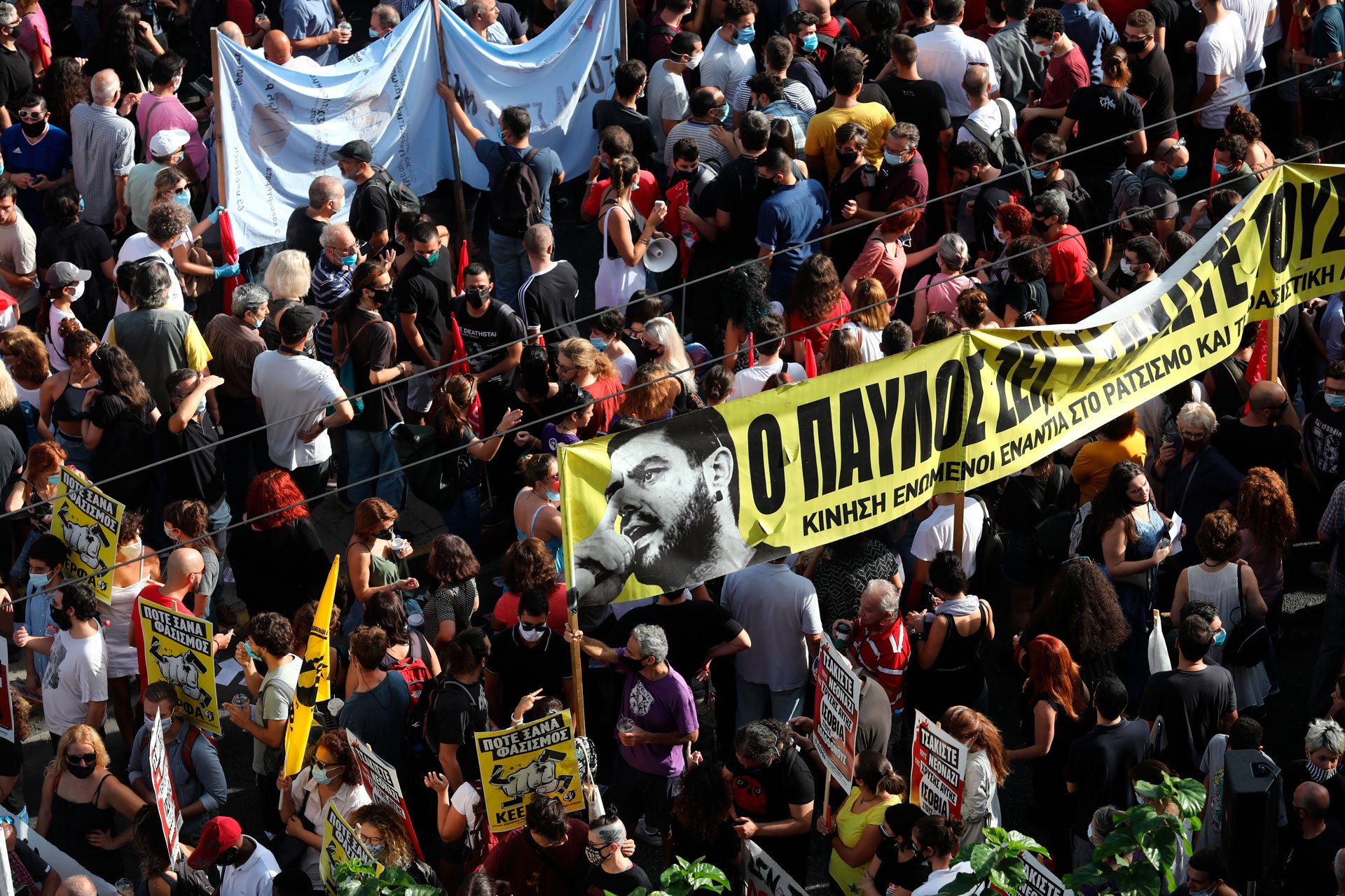 People holding a banner depicting Greek rap singer Pavlos Fyssas, who was stabbed and killed by a supporter of the extreme right Golden Dawn party in 2013, gather for a protest outside a court in Athens, Wednesday, October 7, 2020. 