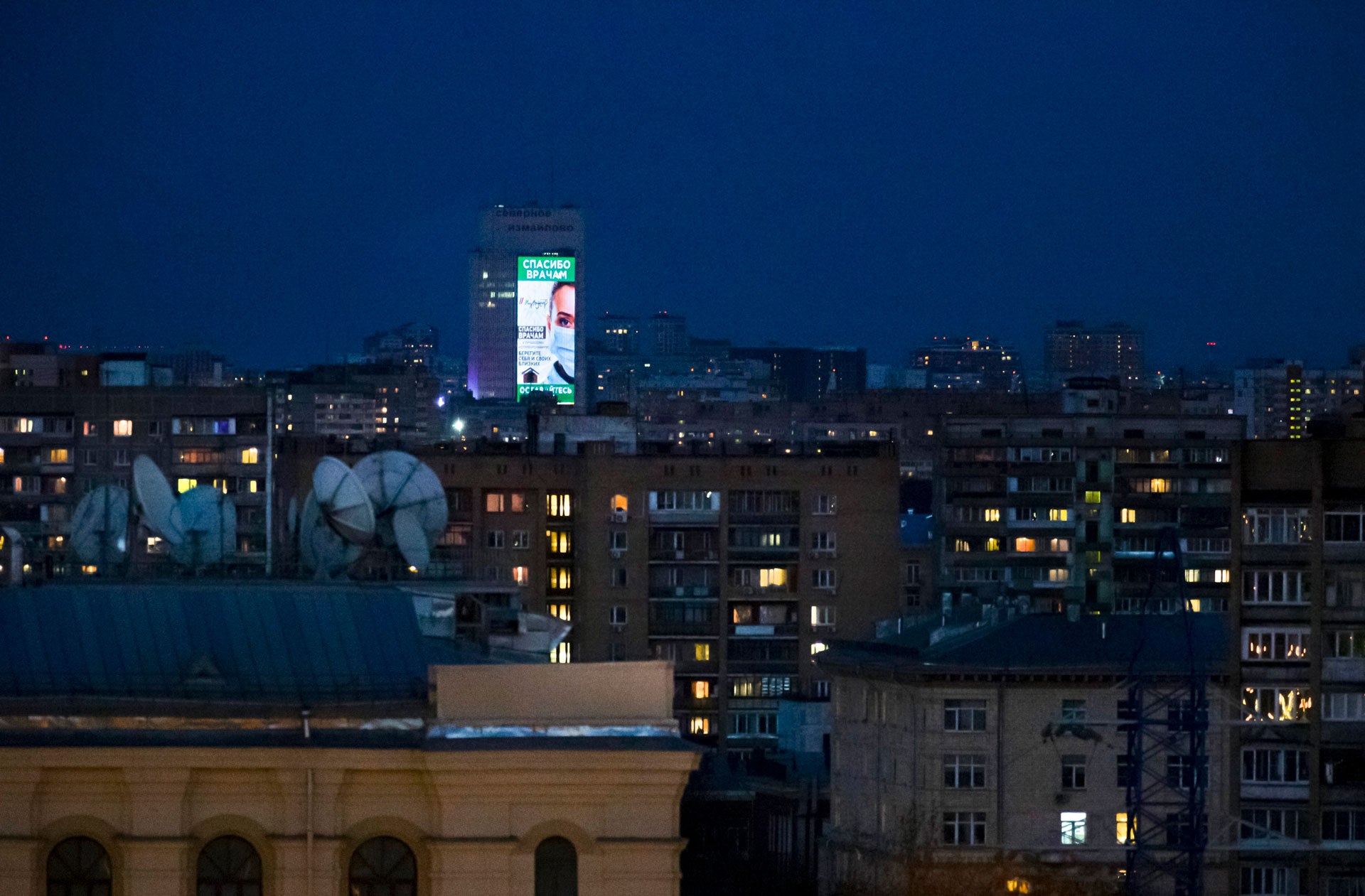 An electronic billboard  is displayed on a office building after sunset in Moscow, Russia, April, 11, 2020. 