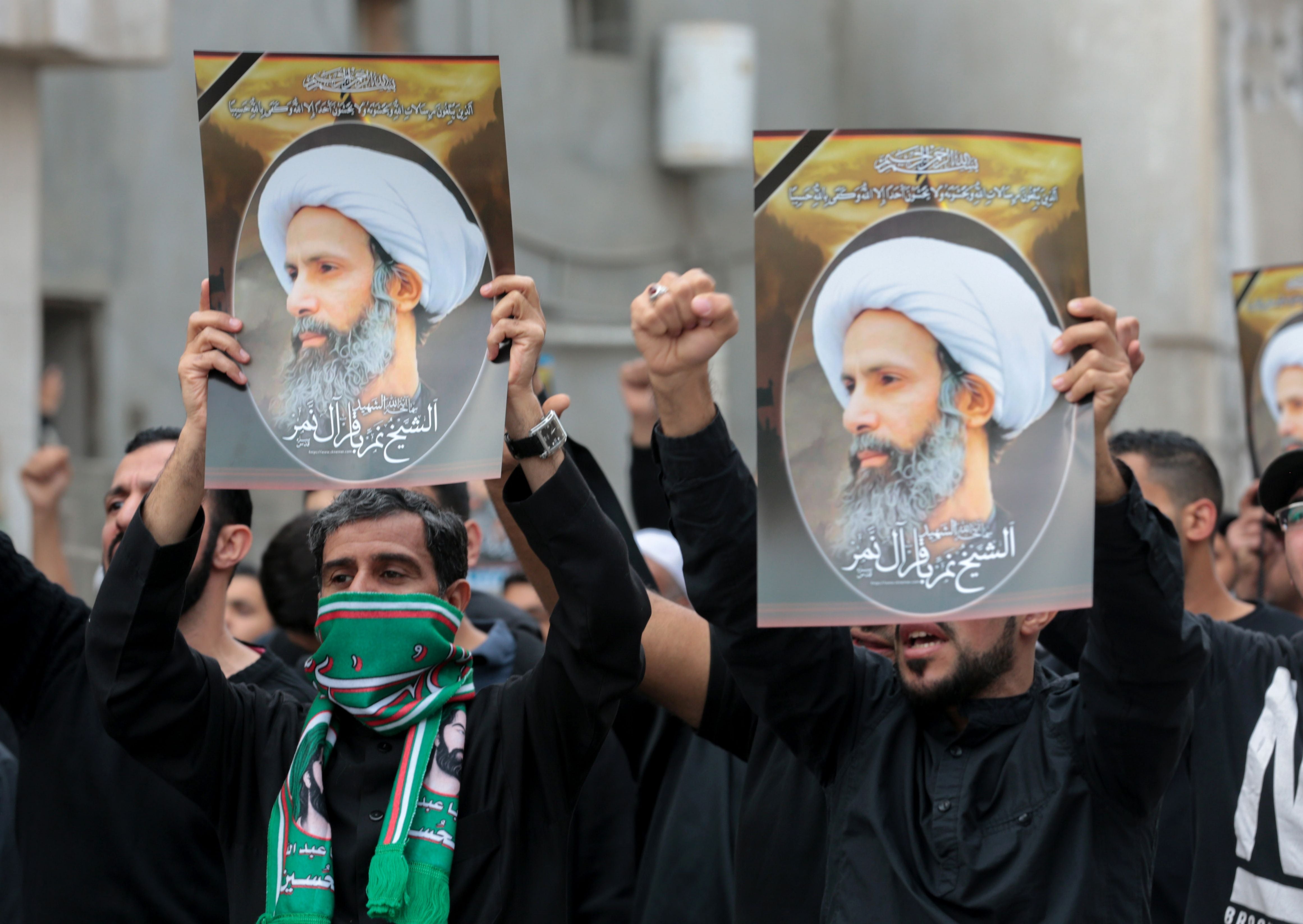 Men hold placards bearing portraits of a prominent Shia Muslim cleric, Nimr al-Nimr, whose execution sparked demonstrations in 2016 by the country's minority Shia citizens against systematic governmental discrimination. Some of the alleged child offenders currently on trial were accused of attending similar protests. 