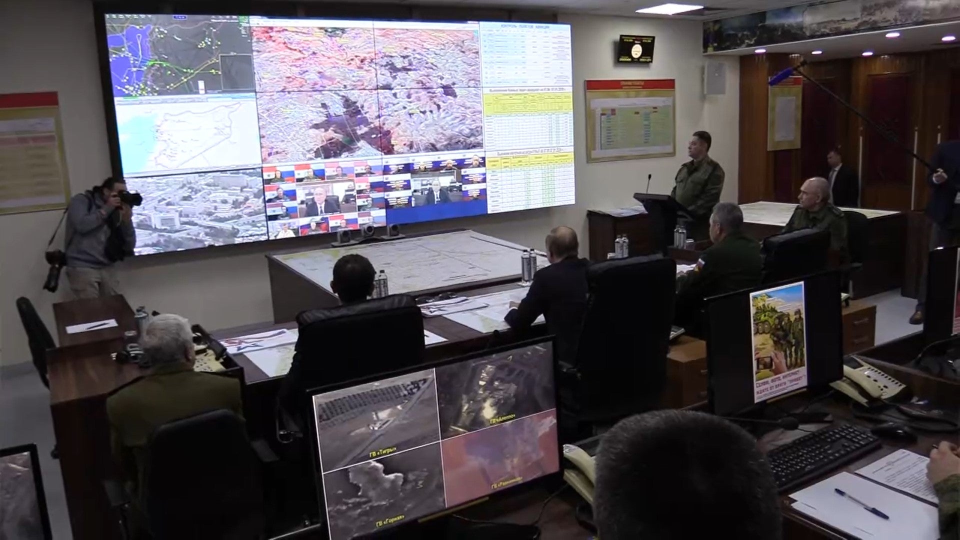 Men at a table watch a video briefing