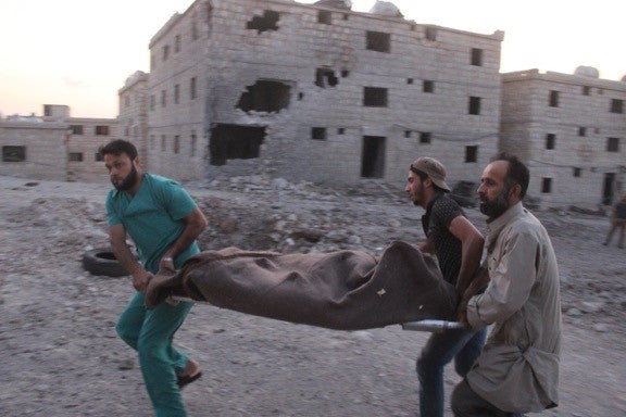 Three men carry a covered body on a stretcher