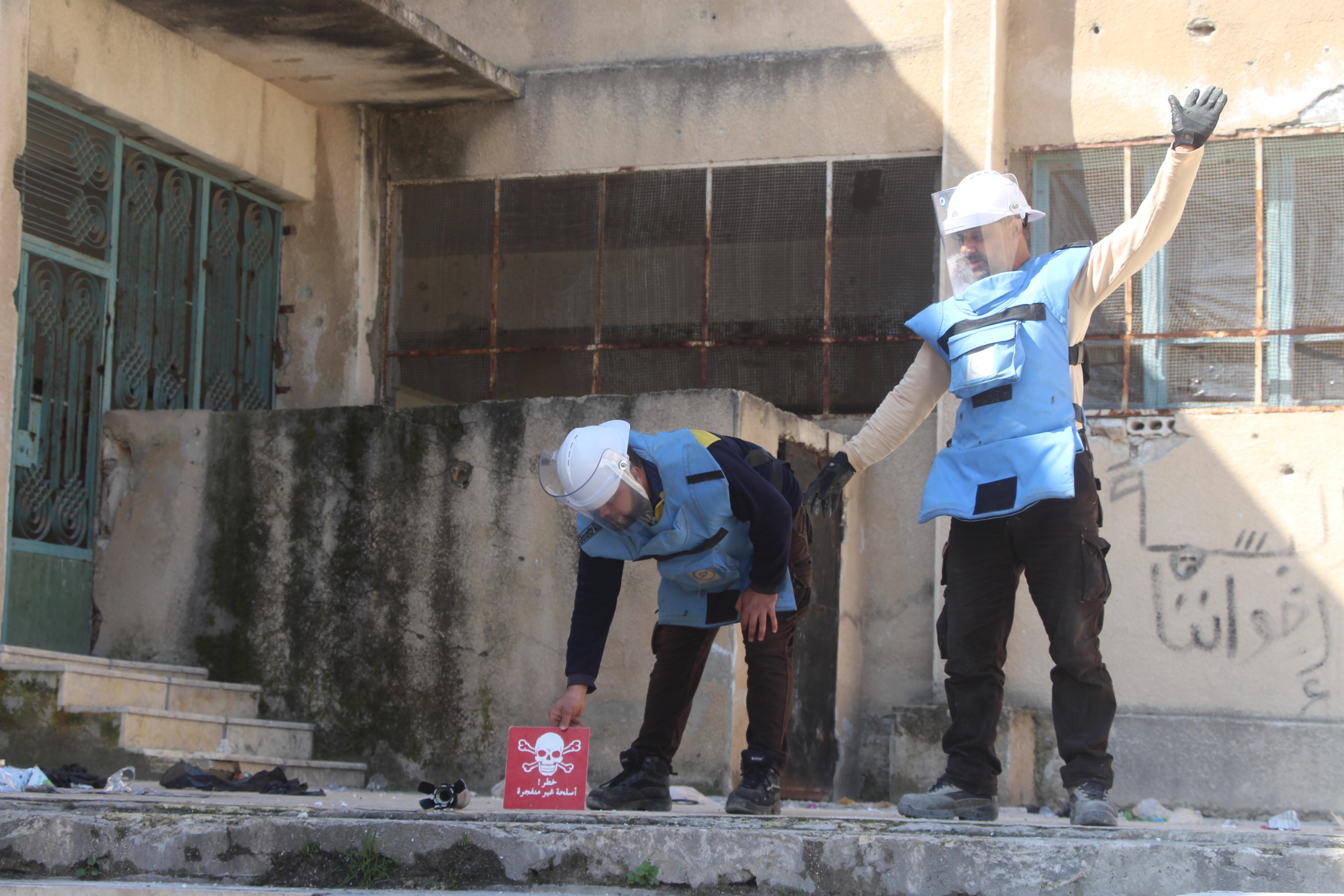 Two men in protective gear stand in a schoolyard