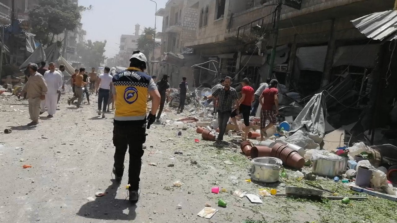 People walk through a destroyed market