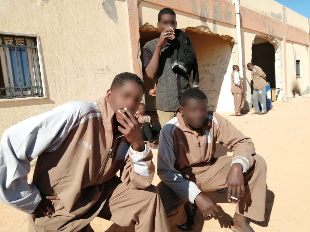 Men pose for a photo outside of a building in the desert