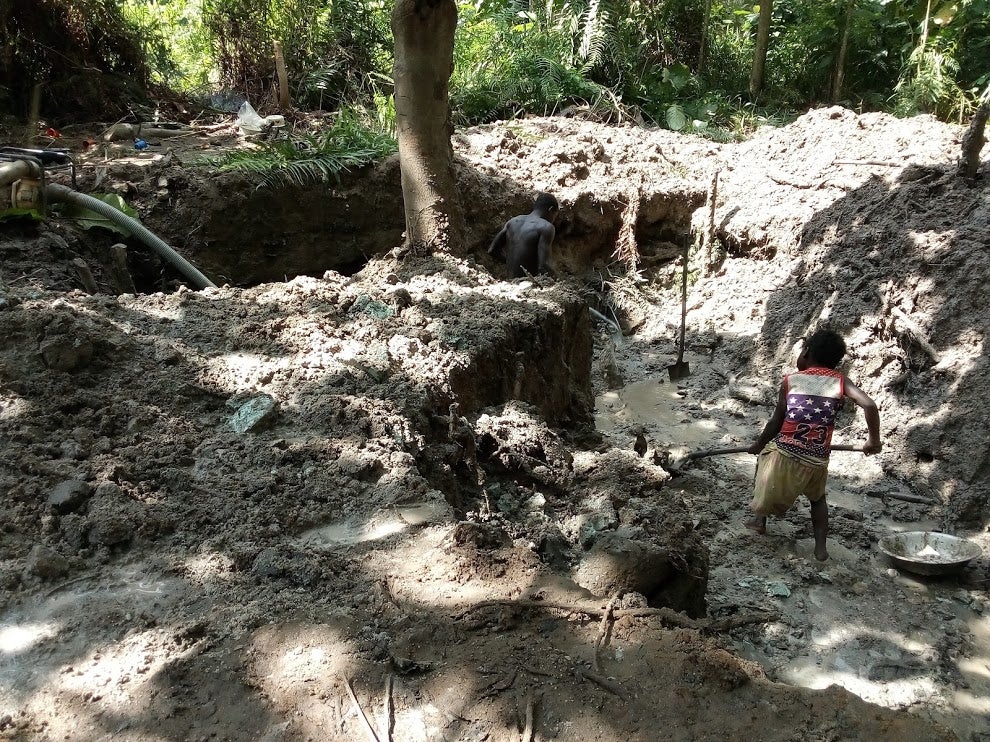 A child holds a mining tool in a rural mine