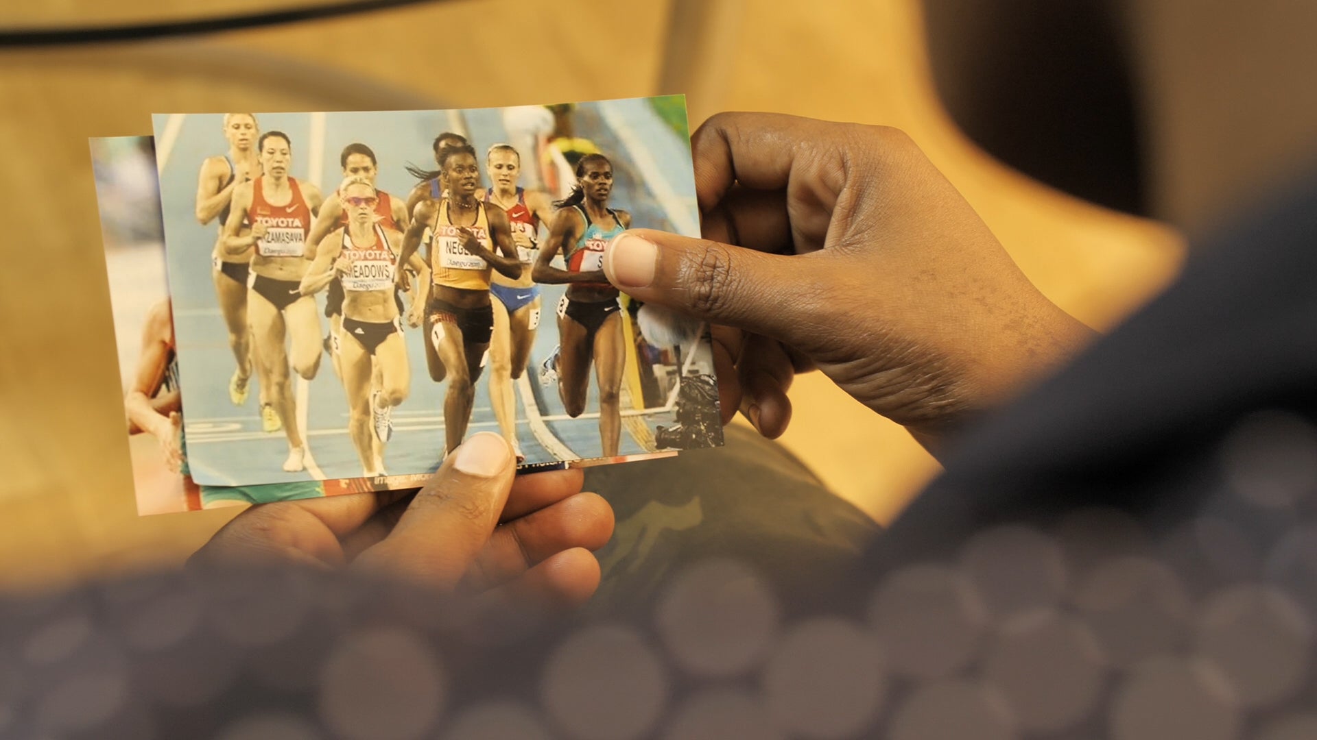 Annet Negesa, corredora de Uganda, segura uma foto sua competindo no Mundial de Atletismo de 2011 em Daegu, Coreia do Sul. Negesa foi alvo de regulamentos de teste de sexo e instruída a se submeter a uma cirurgia clinicamente desnecessária em 2012.