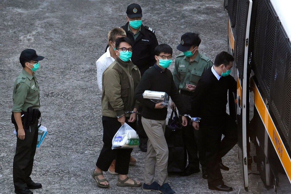 Joshua Wong, center right, and Ivan Lam, center left, were led into a prison van before their court appearance in Hong Kong on Wednesday.