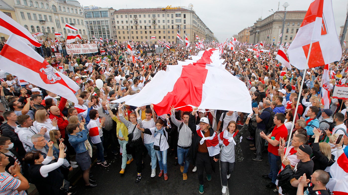 Демонстранты несут большой исторический флаг Беларуси. 23 августа 2020 г. тысячи людей вышли на протест на площади Независимости в Минске, Беларусь.
