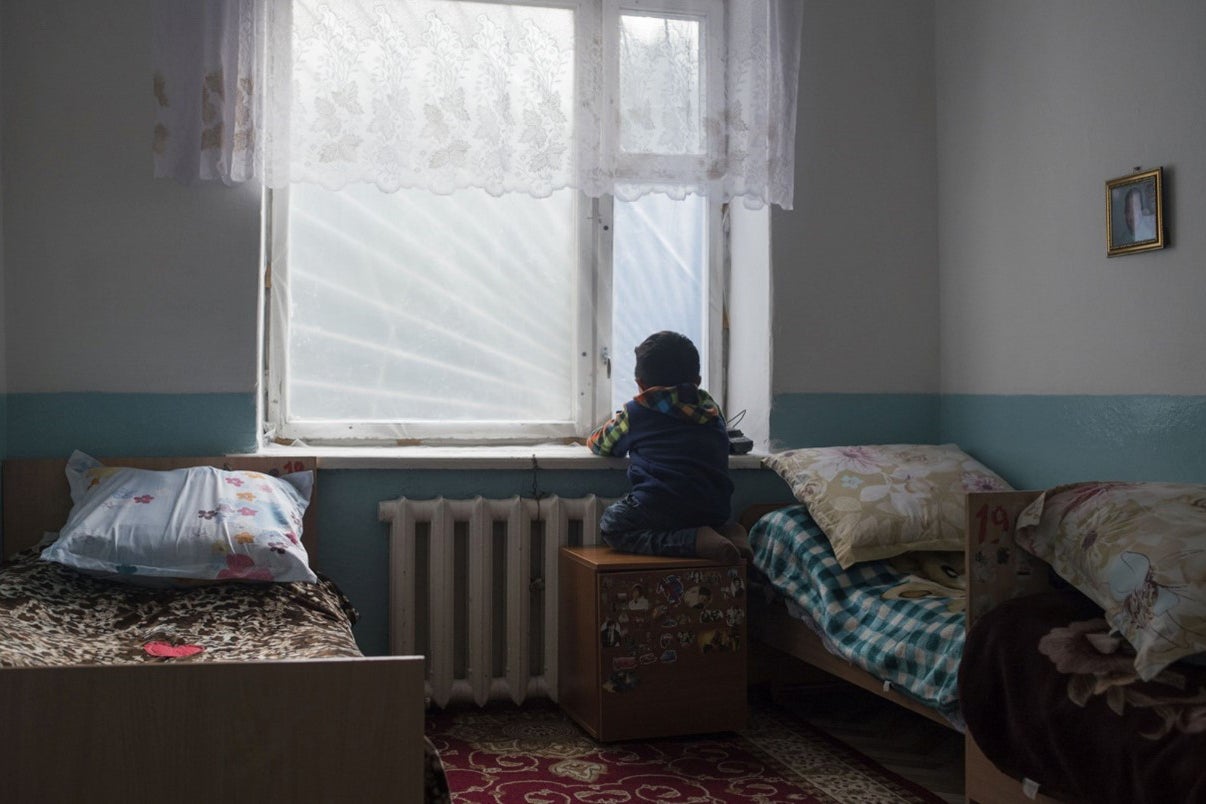A child stares out a bedroom window