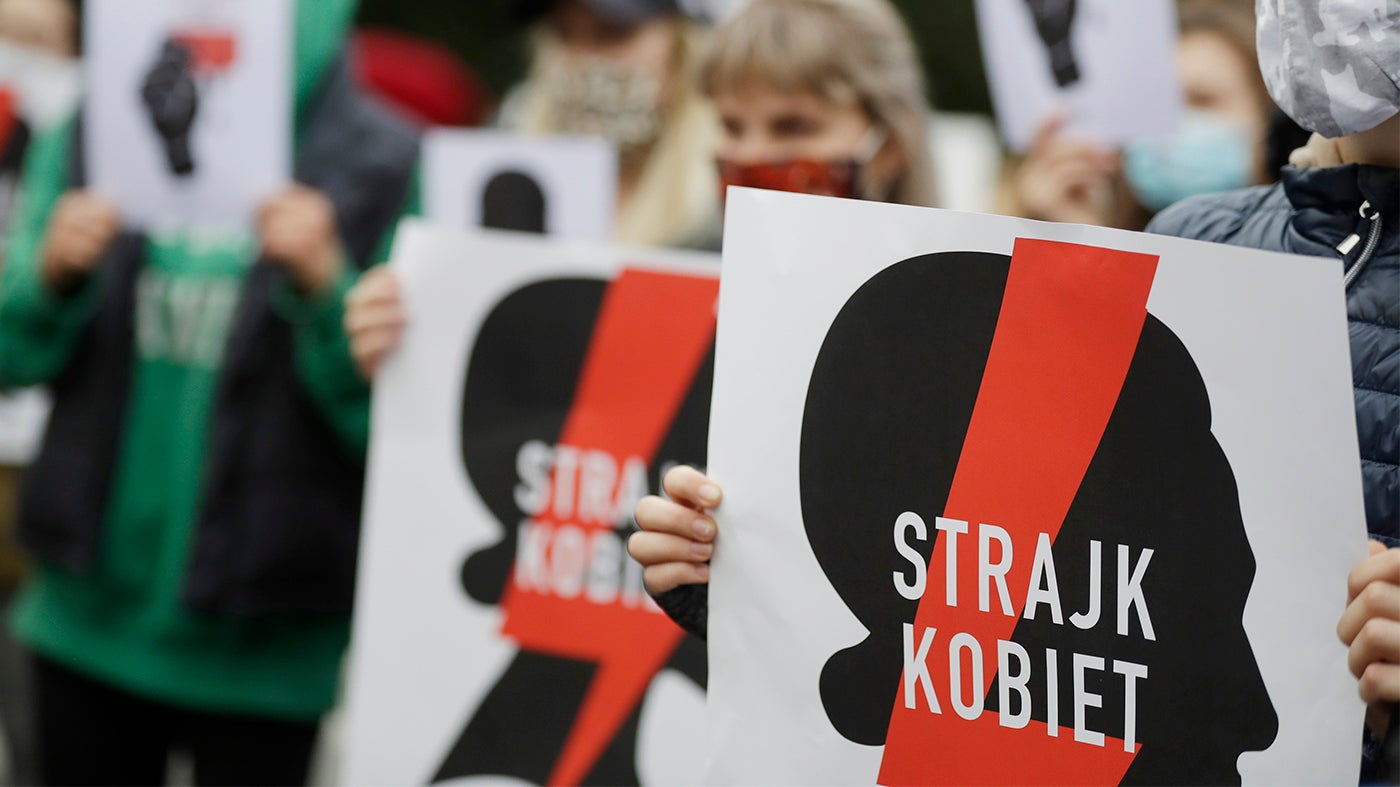Women's rights activists, holding posters of the Women's Strike action, protest further tightening of Poland's restrictive abortion law in front of the parliament building in Warsaw, Poland, on Tuesday, October 27, 2020. 