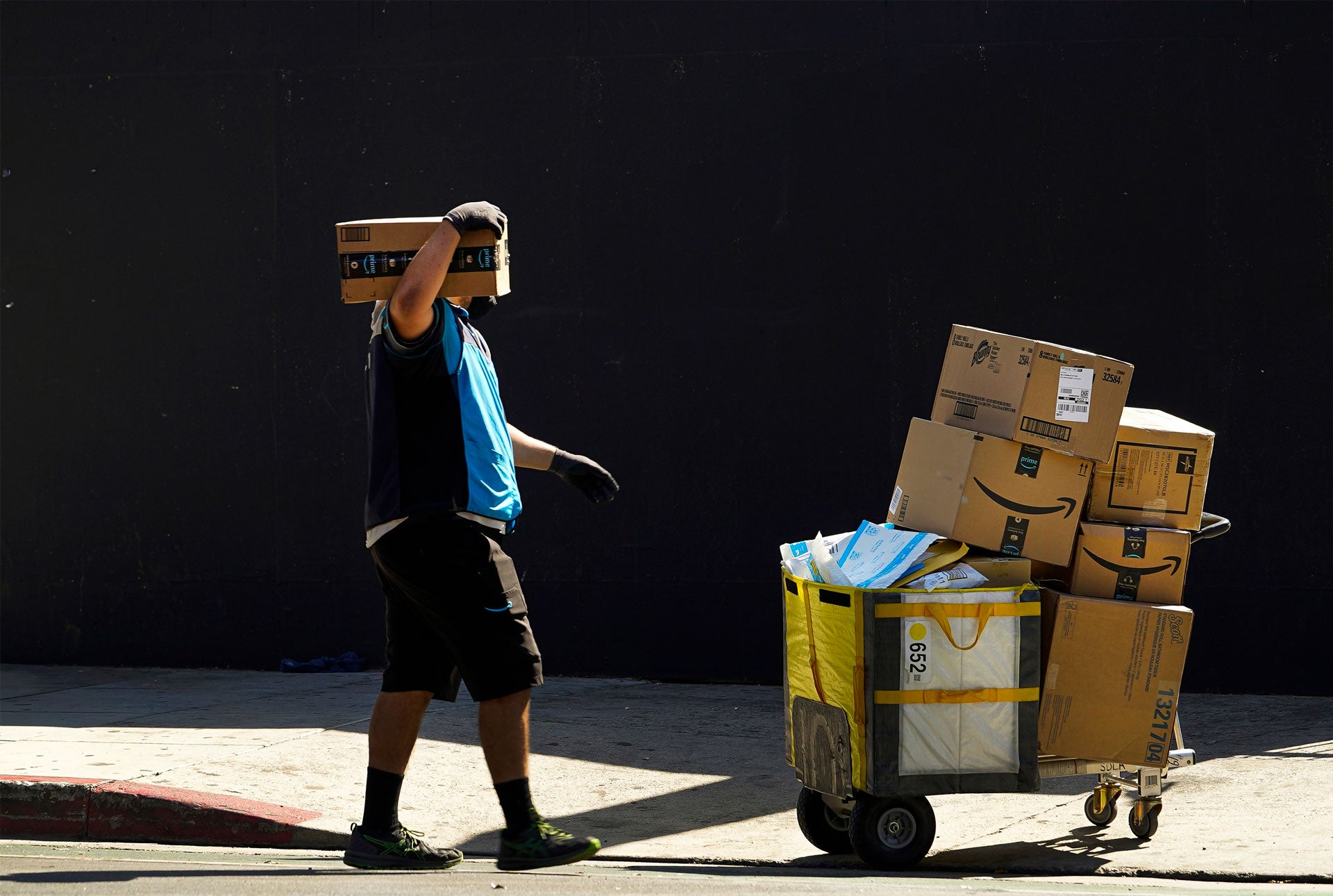 An Amazon worker delivers boxes in downtown Los Angeles, California, October 1, 2020. 
