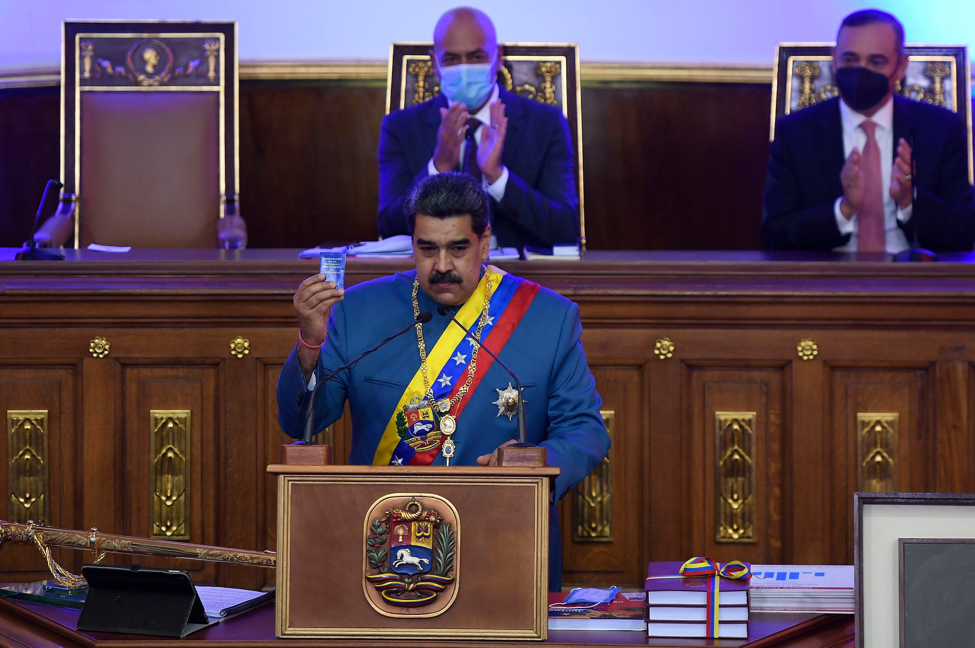 Venezuela's Nicolás Maduro holds a copy of the constitution during his annual address to the nation before lawmakers at the National Assembly in Caracas, Venezuela, Tuesday, Jan. 12, 2021.