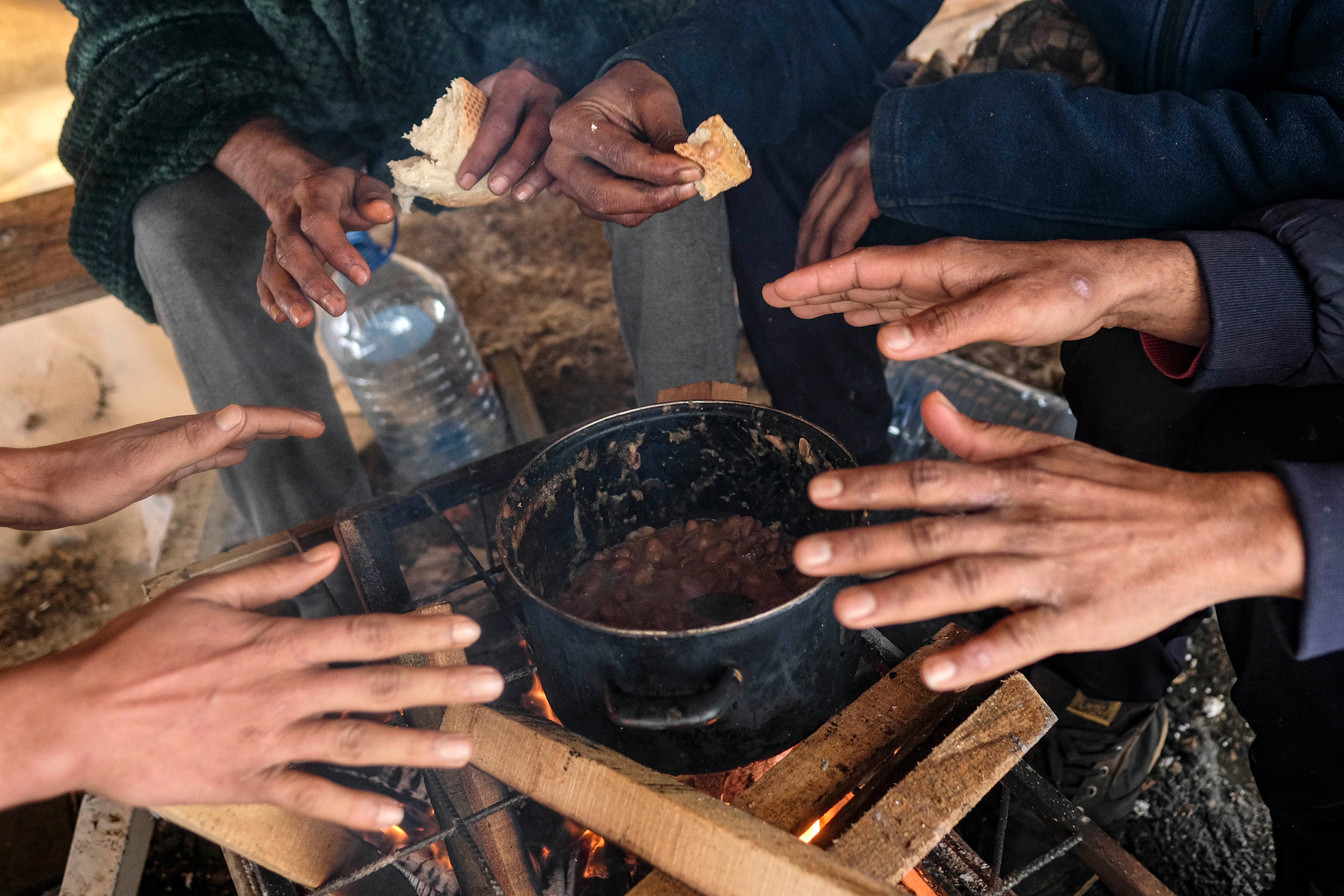 Migrants warm their hands above a fire at the Lipa camp, outside Bihac, Bosnia and Herzegovina, Monday, January 11, 2021. The camp was closed on December 23, 2020 and destroyed in a fire the same day. 