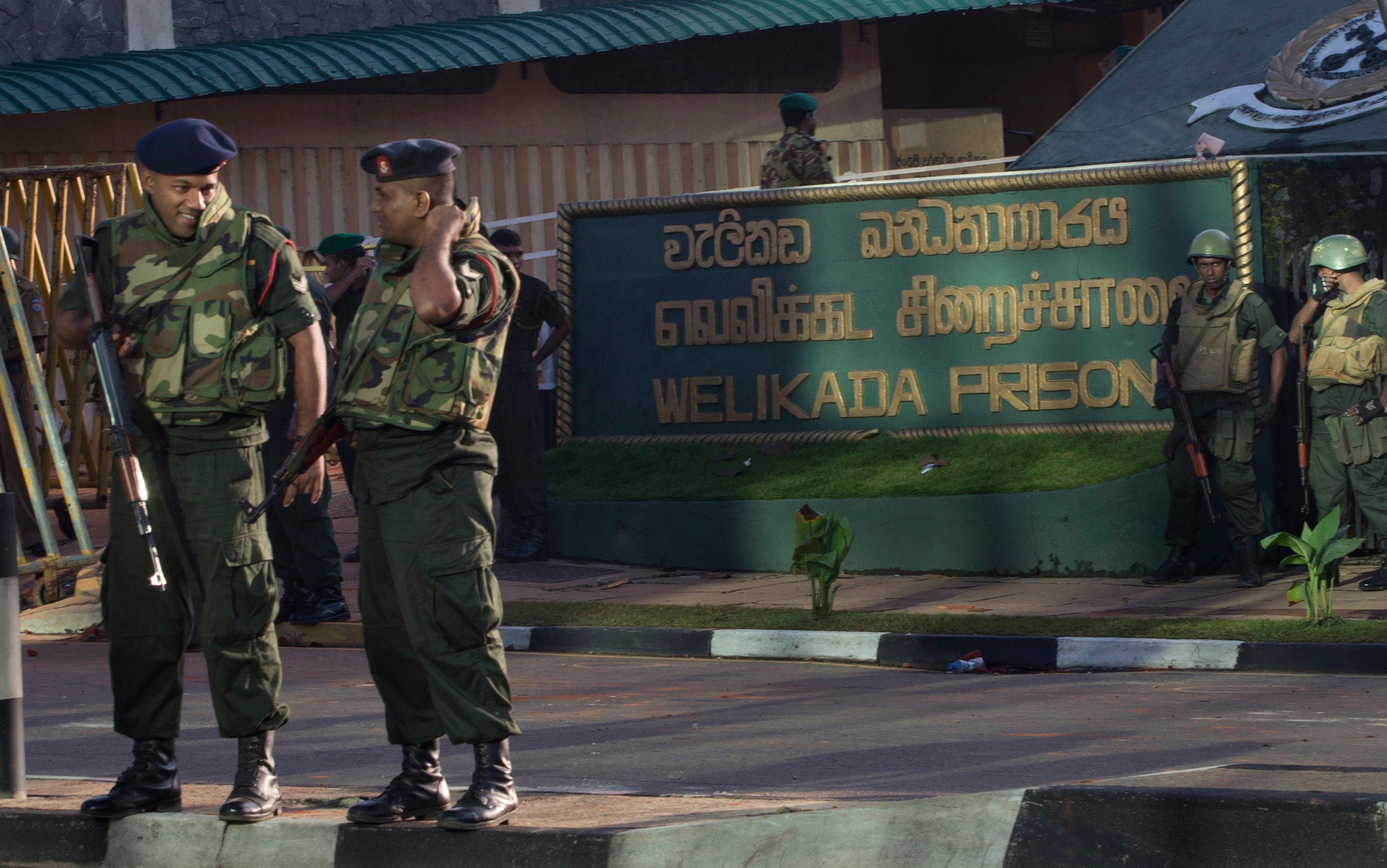 Armed soldiers stand in front of a building with a sign that reads "Welikada Prison"