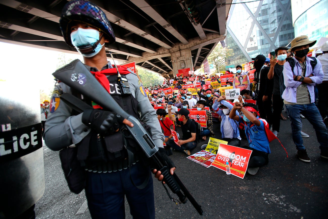 A police officer stands in front of anti-coup protesters in Yangon, Myanmar, February 19, 2021.