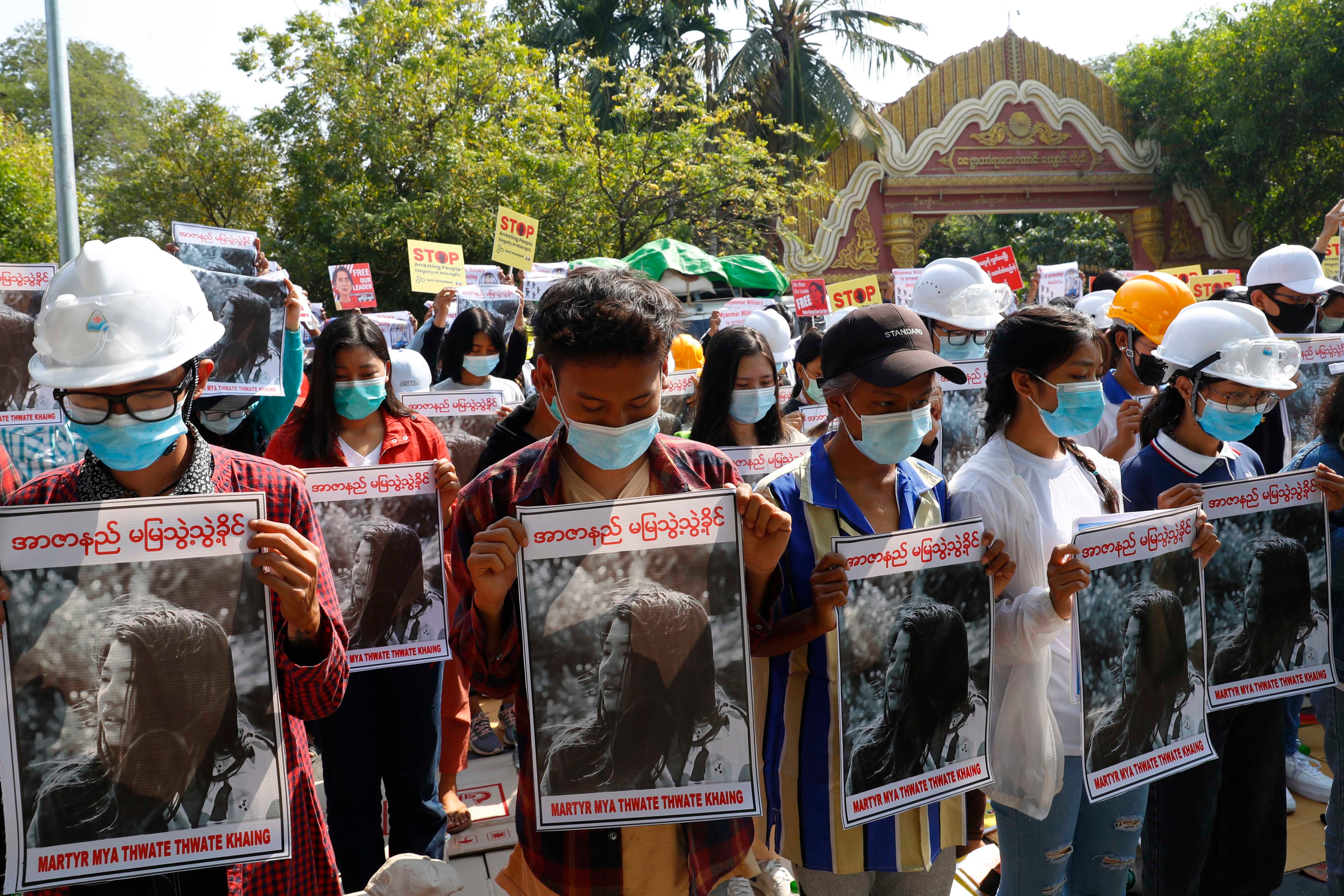 Mandalay University graduates bow their heads as they hold posters of Mya Thwet Thwet Khine, a 19-year-old woman fatally shot by police on February 9 in Naypyidaw, during an anti-coup protest in Mandalay, Myanmar, February 14, 2021. 