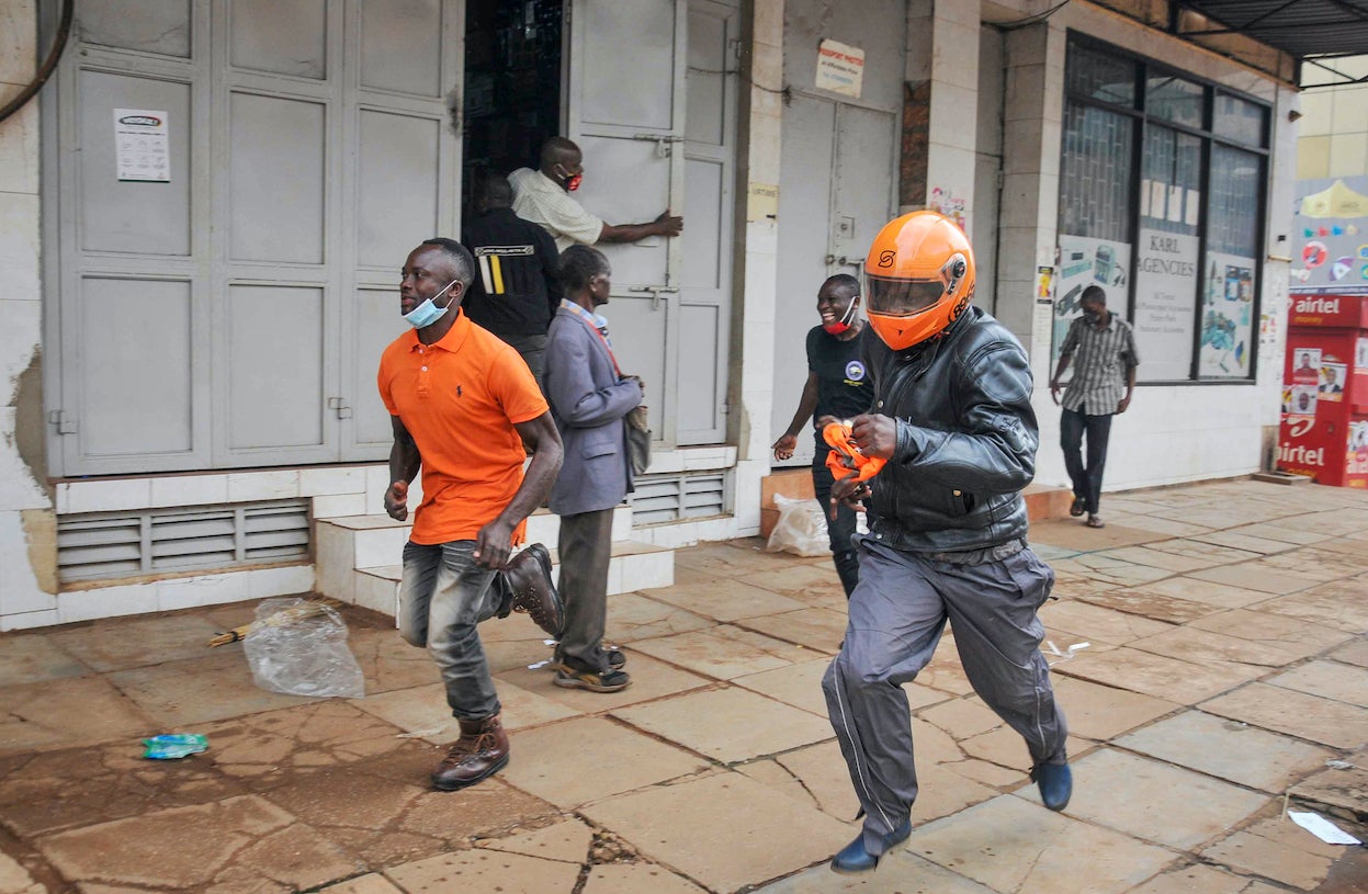 People in Uganda’s capital Kampala flee on November 18, 2020 during clashes between security forces and demonstrators protesting the arrest of opposition candidate Robert Kyagulanyi for allegedly breaching Covid-19 regulations by mobilizing large crowds for his campaign rallies.  