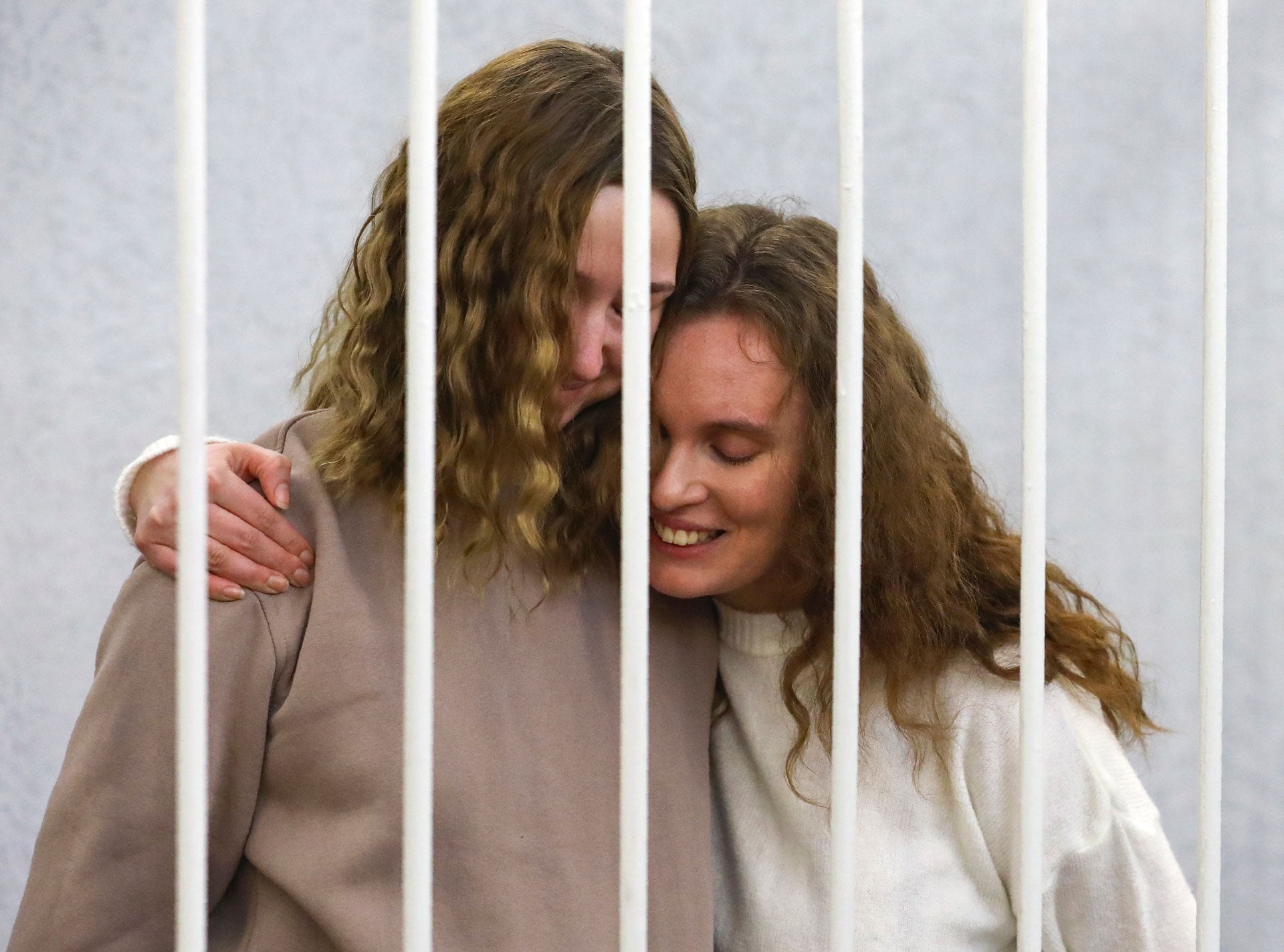 Журналистки Екатерина Андреева (Бахвалова) (справа) и Дарья Чульцова обнимаются в клетке подсудимых во время судебного заседания в Минске 9 февраля 2021 года.