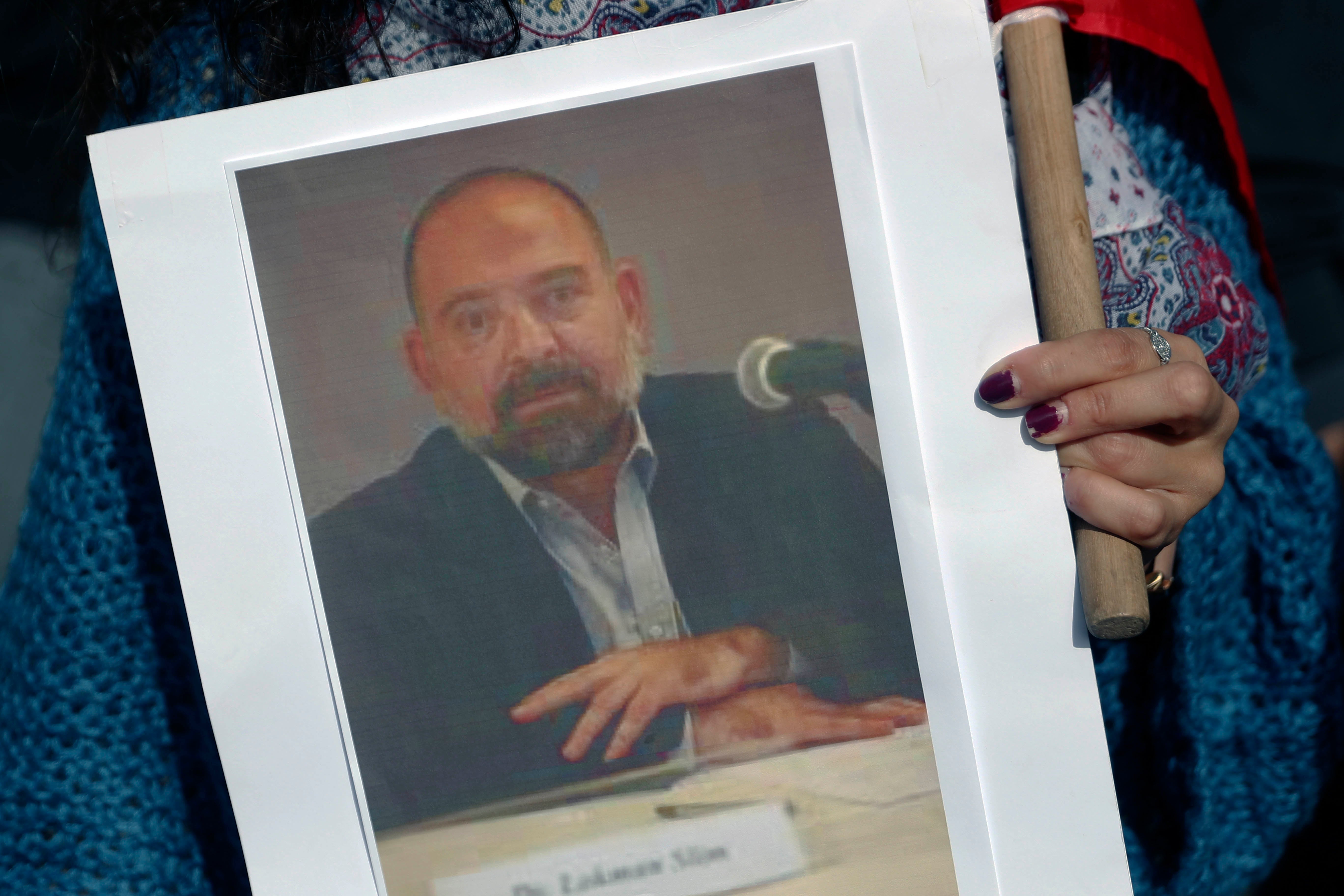 A protestor holds a picture of Lokman Slim, a writer and Hezbollah critic who was found murdered on February 4, 2021.