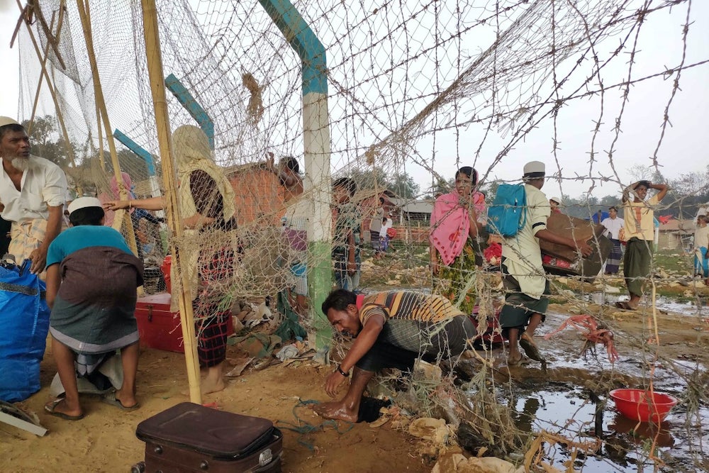 A man climbs through barbed wire fencing at a Rohingya refugee camp in Cox’s Bazar, Bangladesh, as a massive fire swept through the camps on March 22, 2021.