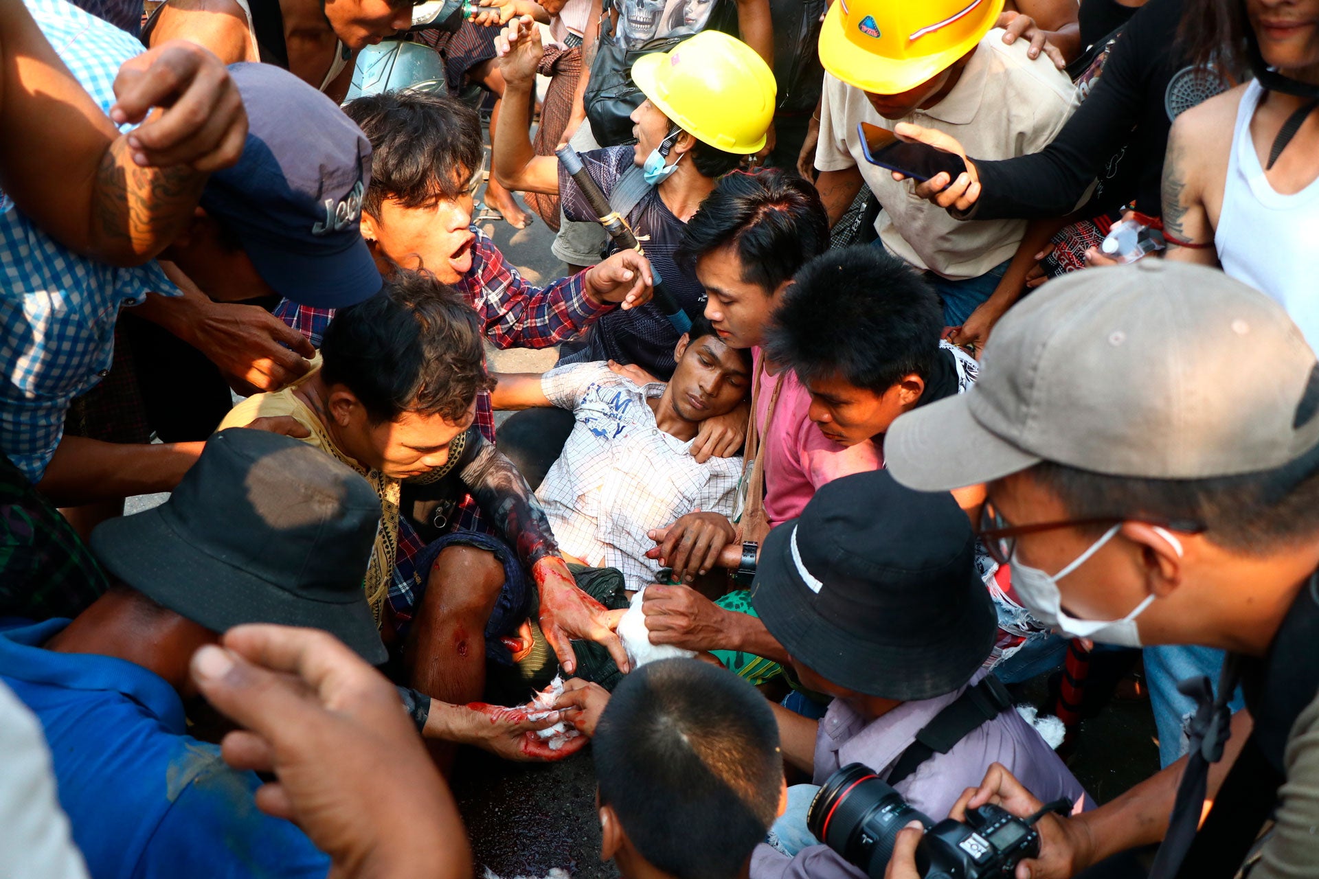 Protesters surround an injured man in Hlaing Tharyar township in Yangon, Myanmar, March 14, 2021.