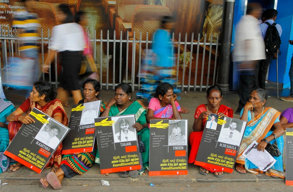 In this April 6, 2015, file photo, Sri Lankan ethnic Tamil women sit holding placards with portraits of their missing relatives as they protest out side a railway station in Colombo, Sri Lanka.