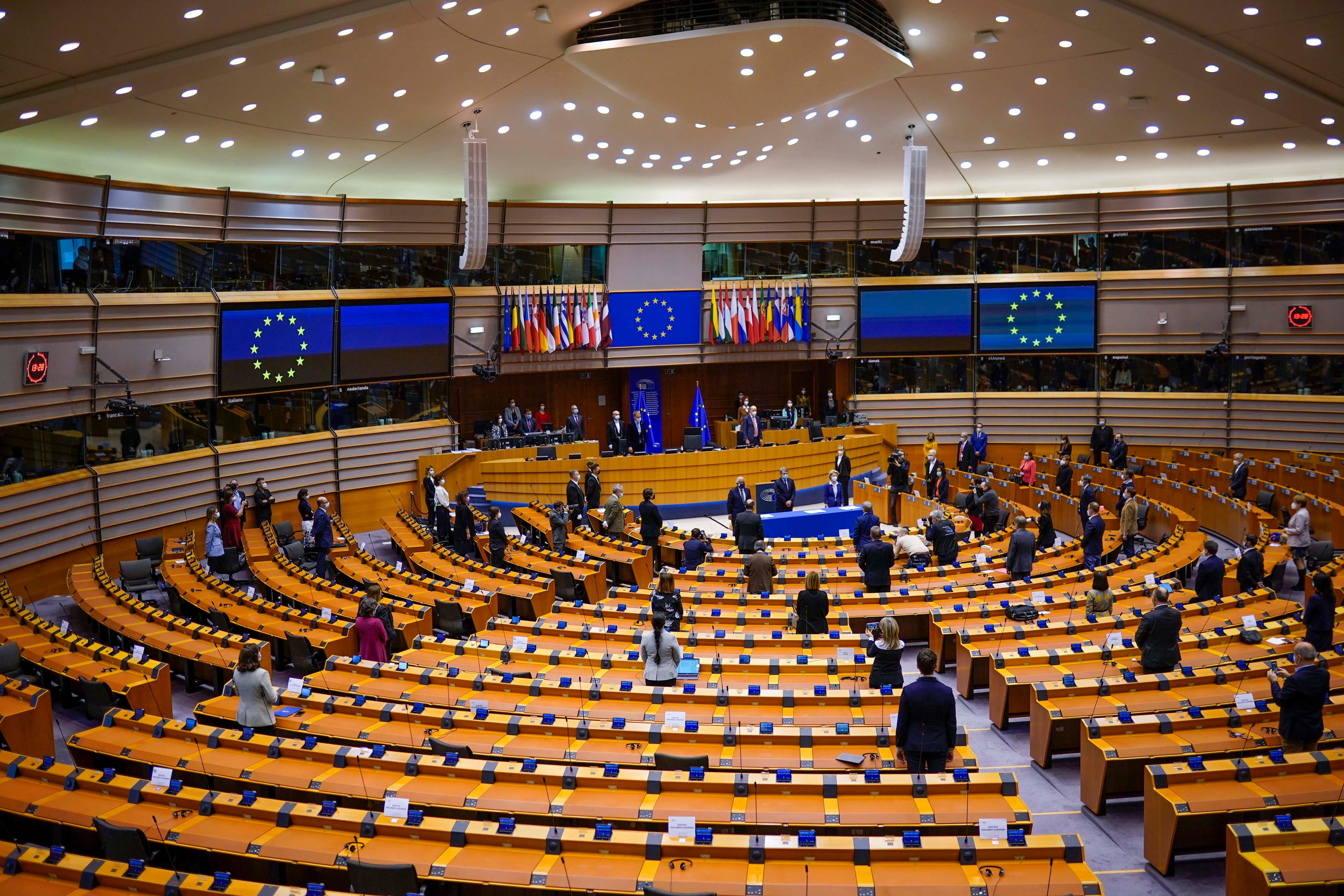 European lawmakers stand up during a signing ceremony at the European Parliament, Brussels, Belgium, March 10, 2021. 